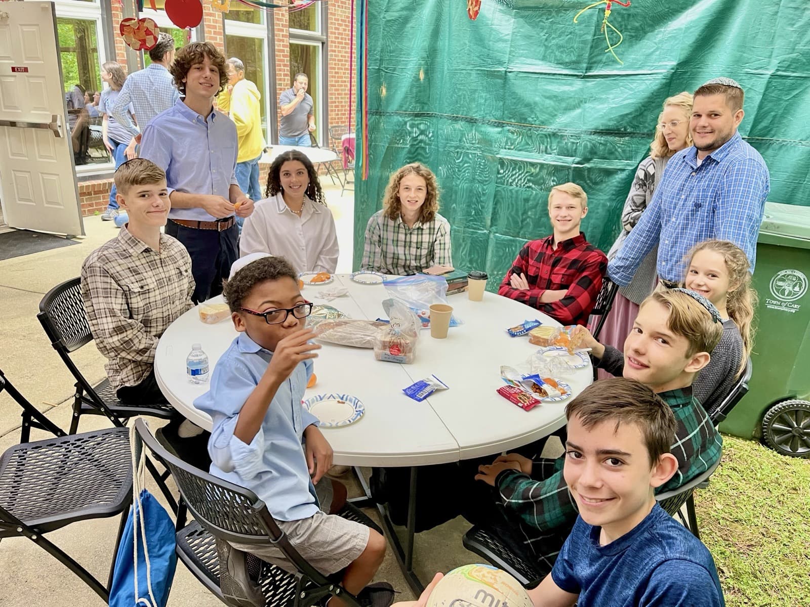 Dorot teens sharing a meal around a table in the sukkah