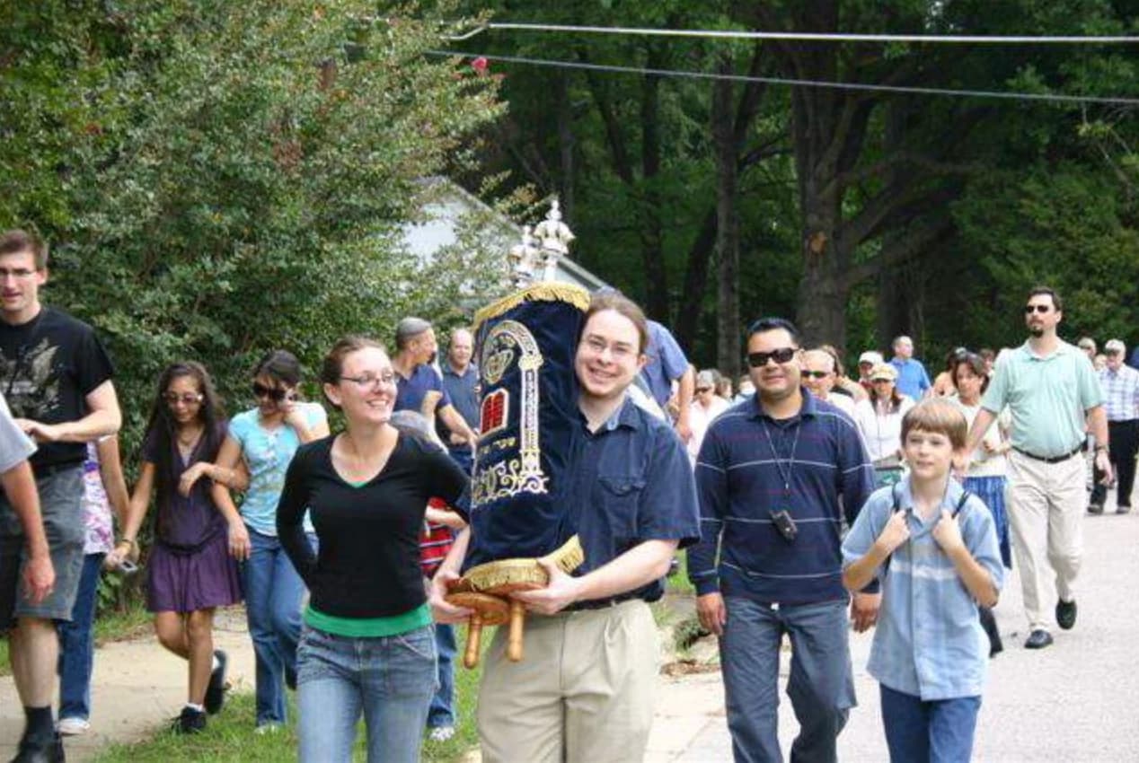 A member smiling as he carries the velvet-covered Torah scroll during the 2008 Torah Walk