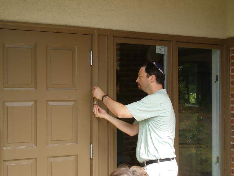 A member affixing the mezuzah to the doorpost of the Old Apex Road building