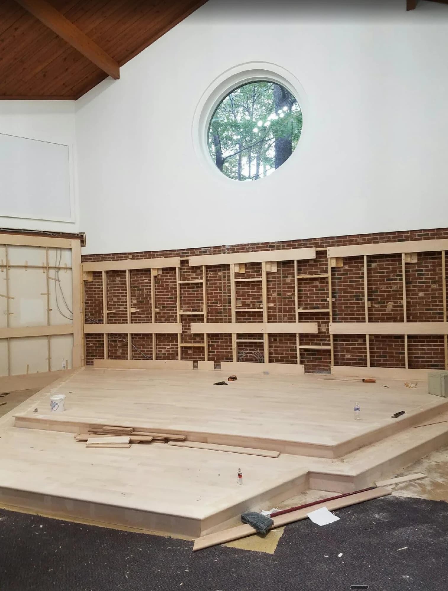 The new maple bimah platform freshly laid beneath the exposed brick wall and round window