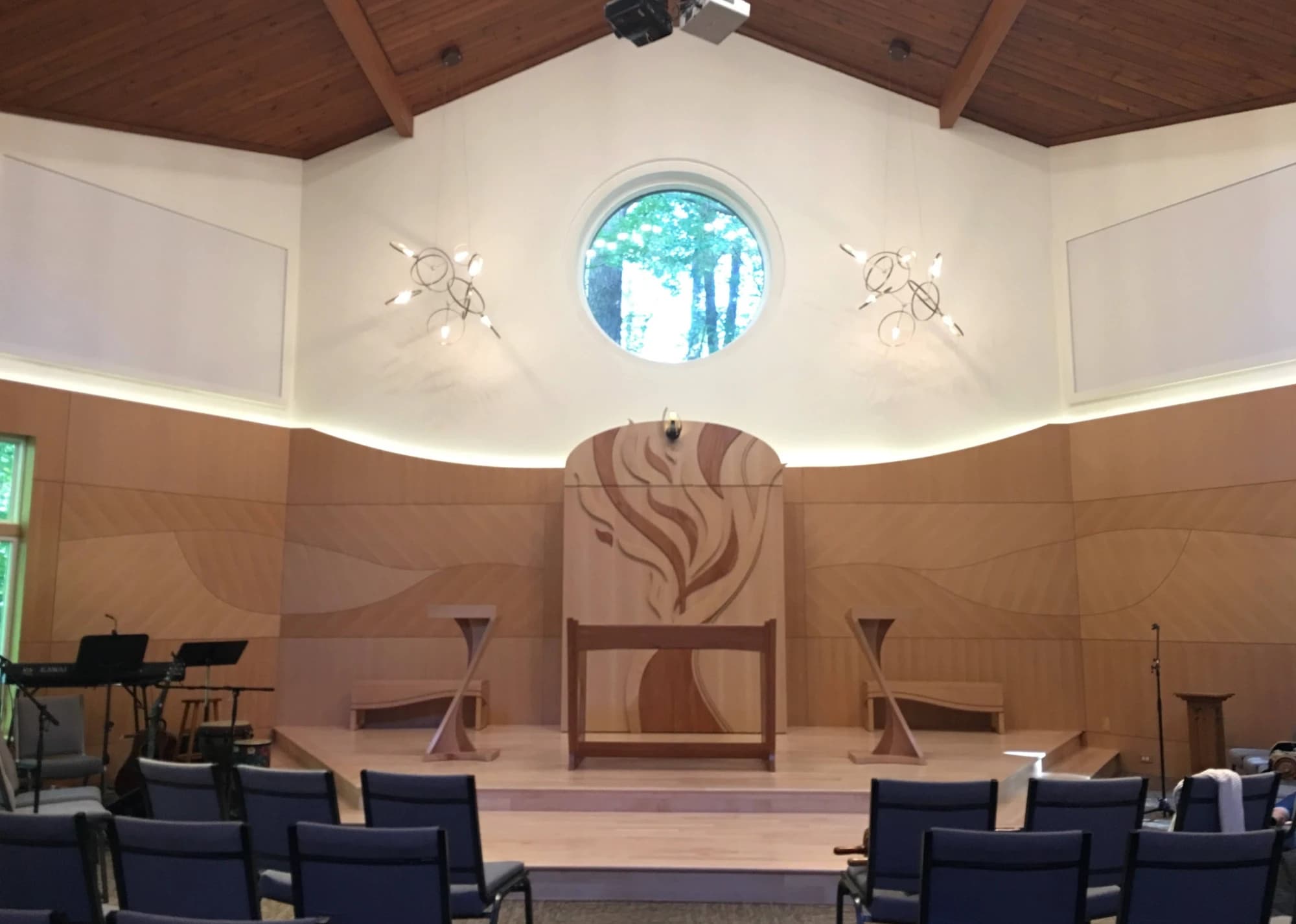 The finished sanctuary: wood-paneled wall with a flame inlay behind the Ark, beneath the round window